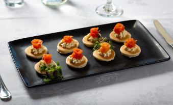 a dining table with a black tray filled with small appetizers , including mini shrimp appetizers at Tides Hotel