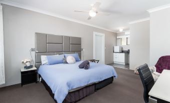 a large bedroom with a bed , blue comforter , and grey carpet , along with a kitchen area in the background at Archibald Hotel