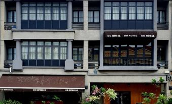 a modern hotel building with a large sign above the entrance and multiple floors , surrounded by plants at Go Hotel