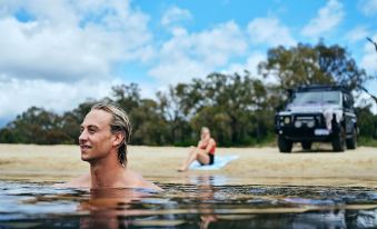 a man and a woman are enjoying a swim in a river , with the truck in the background at Black Diamond Lodge