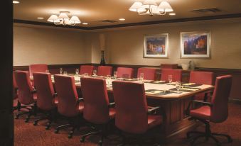 a conference room with a long wooden table , red chairs , and paintings on the wall at DoubleTree by Hilton Hotel Cincinnati Airport