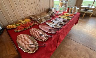 a table is set with a variety of food items , including sausage and fruit , in a room with wooden walls at Hörgsland Cottages