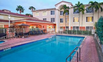 an outdoor swimming pool surrounded by a building , with palm trees in the background at Residence Inn Fort Lauderdale Weston