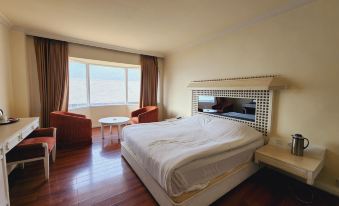a spacious bedroom with a large bed , wooden floors , and a view of the ocean through a window at WoodStock Hotel