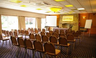 a conference room set up for a meeting , with rows of chairs arranged in front of a projector screen at Alton House Hotel