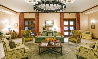 a spacious living room with multiple couches , chairs , and a chandelier hanging from the ceiling at Hotel Viata