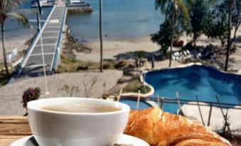 a cup of coffee and a croissant are placed on a table with a view of the ocean at Marina Del Ray