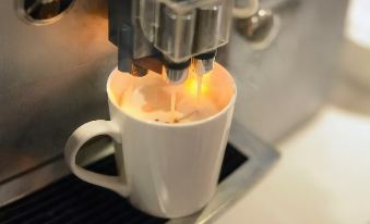 a white coffee cup being roasted on a stove , with steam rising from the mug at Le Room Hotel Taoyuan