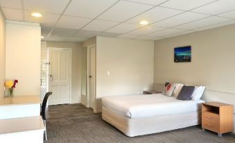 a large bed with white linens is in a room with a desk , chair , and television at Garden Hotel