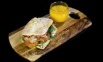 a wooden cutting board with a sandwich on it , accompanied by a glass of orange juice at Maruia Hot Springs