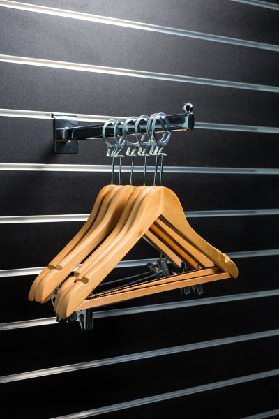 a row of wooden hangers hanging on a metal rack against a black and white striped wall at Village Hotel Liverpool