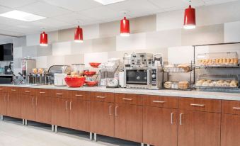 a modern kitchen with wooden cabinets , a counter filled with various appliances , and red pendant lights hanging above at Ramada by Wyndham Minneapolis Golden Valley