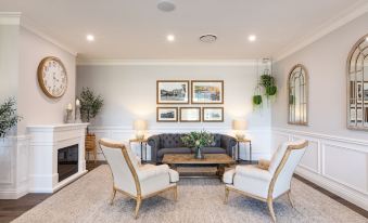 a modern living room with white walls , wooden floors , and two armchairs facing a black couch at Camden Valley Inn