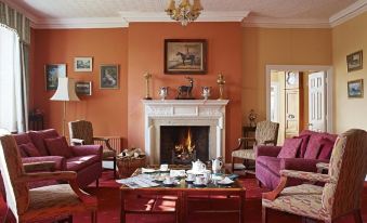 a cozy living room with a fireplace , multiple couches , and chairs arranged around the space at Corse Lawn House Hotel