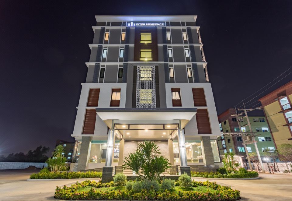 a modern building with a large glass window and a sign above the entrance , illuminated at night at Grand Inter Hotel