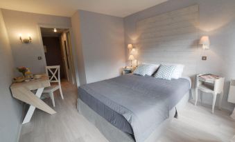 a modern bedroom with a large bed , white bedding , and two lamps on either side of the bed at La Cascade