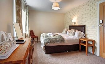 a cozy bedroom with a large bed , a desk , and a chair , surrounded by wooden furniture at The Twice Brewed Inn