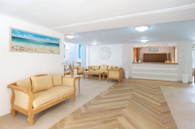 a spacious living room with wooden floors and beige furniture , including couches , chairs , and a dining table at Hotel Summery