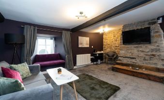 a modern living room with a purple couch , gray walls , and a fireplace is shown at The Ancient Unicorn