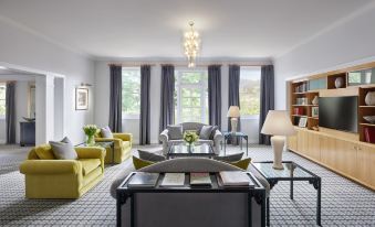 a spacious living room with multiple chairs , a couch , and a tv . the room is well - organized and well - maintained at Hyatt Hotel Canberra - A Park Hyatt Hotel