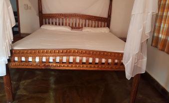 a wooden bed with a white sheet and two pillows , surrounded by a white curtain at Blue Rooms