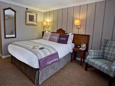 a large bed with a purple and white striped blanket is in a hotel room at Village Hotel Liverpool