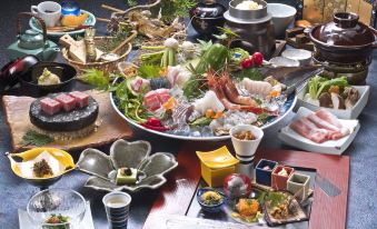 a table is set with various dishes , including a large bowl filled with sushi and a plate of fruit at Shikimitei Fujiya