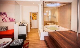 a modern bathroom with a bathtub and a jacuzzi , along with wooden floors and furniture at Gold Reef City Theme Park Hotel