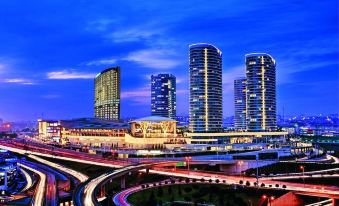 a city skyline with tall buildings and a busy highway in the foreground , illuminated by night lights at Hilton Mall of Istanbul