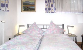 a bed with a pink and purple floral comforter is shown in a bedroom with a window at Paula