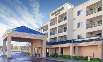 a courtyard by marriott hotel with a covered entrance , surrounded by a parking lot and trees at Courtyard Seattle North/Lynnwood Everett