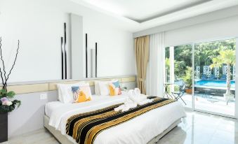 a large bed with white sheets and a black and gold striped blanket is in a room with a sliding glass door at Pimtara Beach Resort