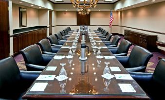a long wooden conference table with multiple chairs , wine glasses , and american flags , set in a conference room at Holiday Inn Wilmington