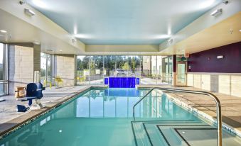 a modern swimming pool area with blue and white tiles , surrounded by large windows and equipped with a diving board at Home2 Suites by Hilton Atlanta Marietta