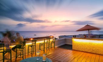 a rooftop terrace with a bar , outdoor dining area , and a stunning ocean view at sunset at Beach View Hotel