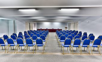 a large conference room with rows of blue chairs arranged in a semicircle , providing seating for a group of people at Hotel Home Green Home