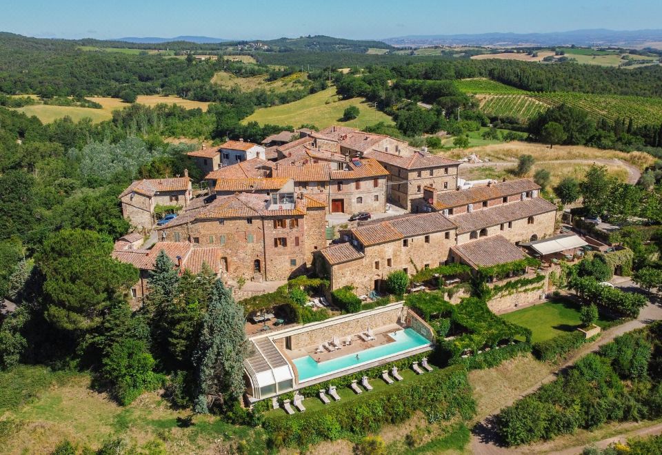 an aerial view of a large , old - fashioned stone house with a pool in the center surrounded by greenery and trees at Bosco Della Spina