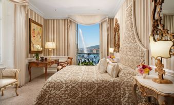 a luxurious bedroom with a king - sized bed , a dresser , and a view of the ocean at Hotel d'Angleterre