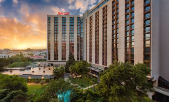 "a large hotel building with a red sign that reads "" sheraton "" is surrounded by trees and bushes" at Lisbon Marriott Hotel