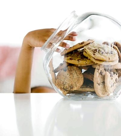 a woman is holding a glass jar filled with chocolate chip cookies , possibly cookies , on a white table at Country Inn & Suites by Radisson, Watertown, SD