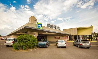 a parking lot with several cars parked in front of a hotel , including one with the tag logo on it at Nightcap at Glengala Hotel