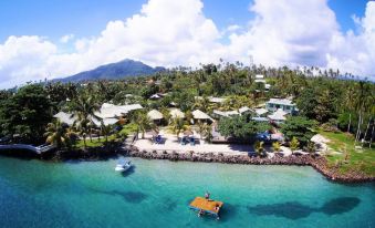 aerial view of a tropical island with a beach , resort , and ocean , surrounded by palm trees and blue water at Le Uaina Beach Resort