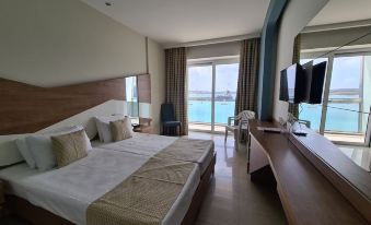 a modern hotel room with two beds , a desk , and a large window overlooking the ocean at Water's Edge Hotel