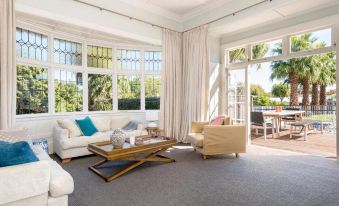 a spacious living room with white walls , large windows , and wooden furniture , including a couch , chairs , and a coffee table at Cedar House