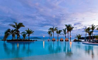 a large swimming pool surrounded by palm trees , with the ocean visible in the background at The Westin Playa Bonita Panama