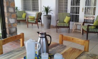 a wooden dining table with a pitcher , cups , and a book placed on it , surrounded by chairs and a door leading to a patio at Urban Lodge