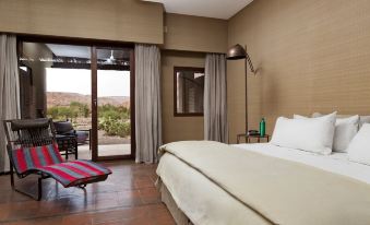 a hotel room with a king - sized bed , a couch , and a door leading to a patio at Nayara Alto Atacama