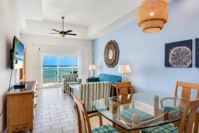 a living room with a couch , chairs , and dining table is shown with a view of the ocean at Wyndham Reef Resort Grand Cayman