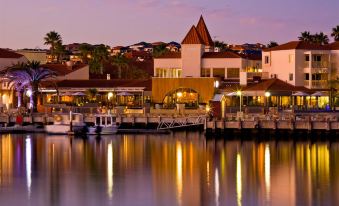 a picturesque waterfront scene with boats docked , houses on the waterfront , and palm trees lining the waterfront at The Marina Hotel - Mindarie