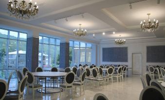 a large dining room with white chairs and tables arranged in a circle , creating a formal setting for a banquet at Grand House hotel & zipline